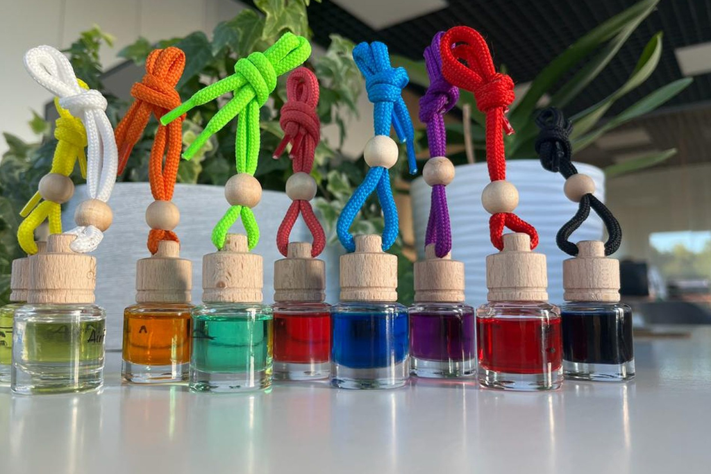 Different car air fresheners in glass bottles in different colours - red, blue, black, clear and turquoise